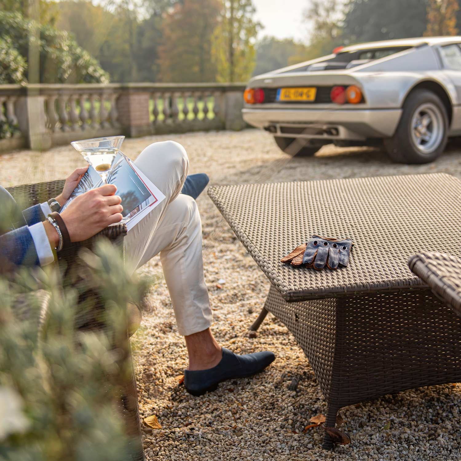 Blue brown Italian handmade driving gloves with in the background a Ferrari 512 BB