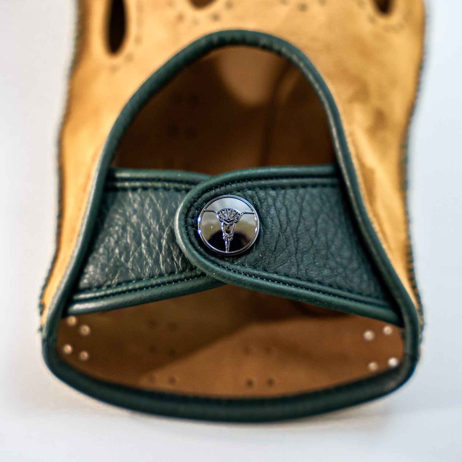 Close-up of a leather glove with green trim and a button on a white background