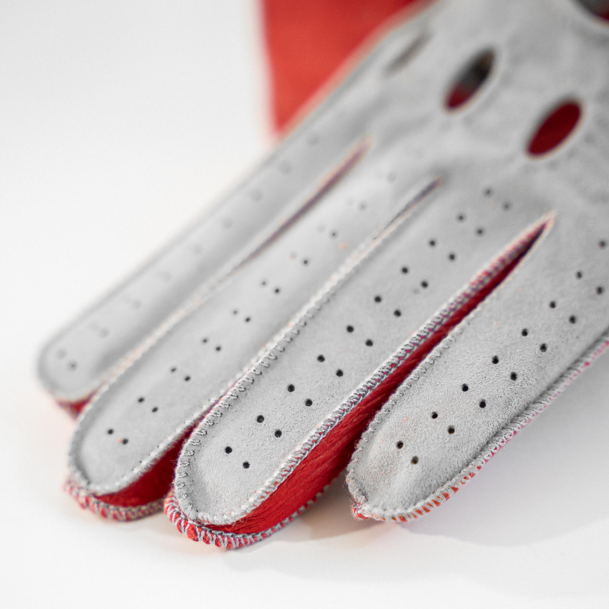 Gray driving gloves with red accents on a white background