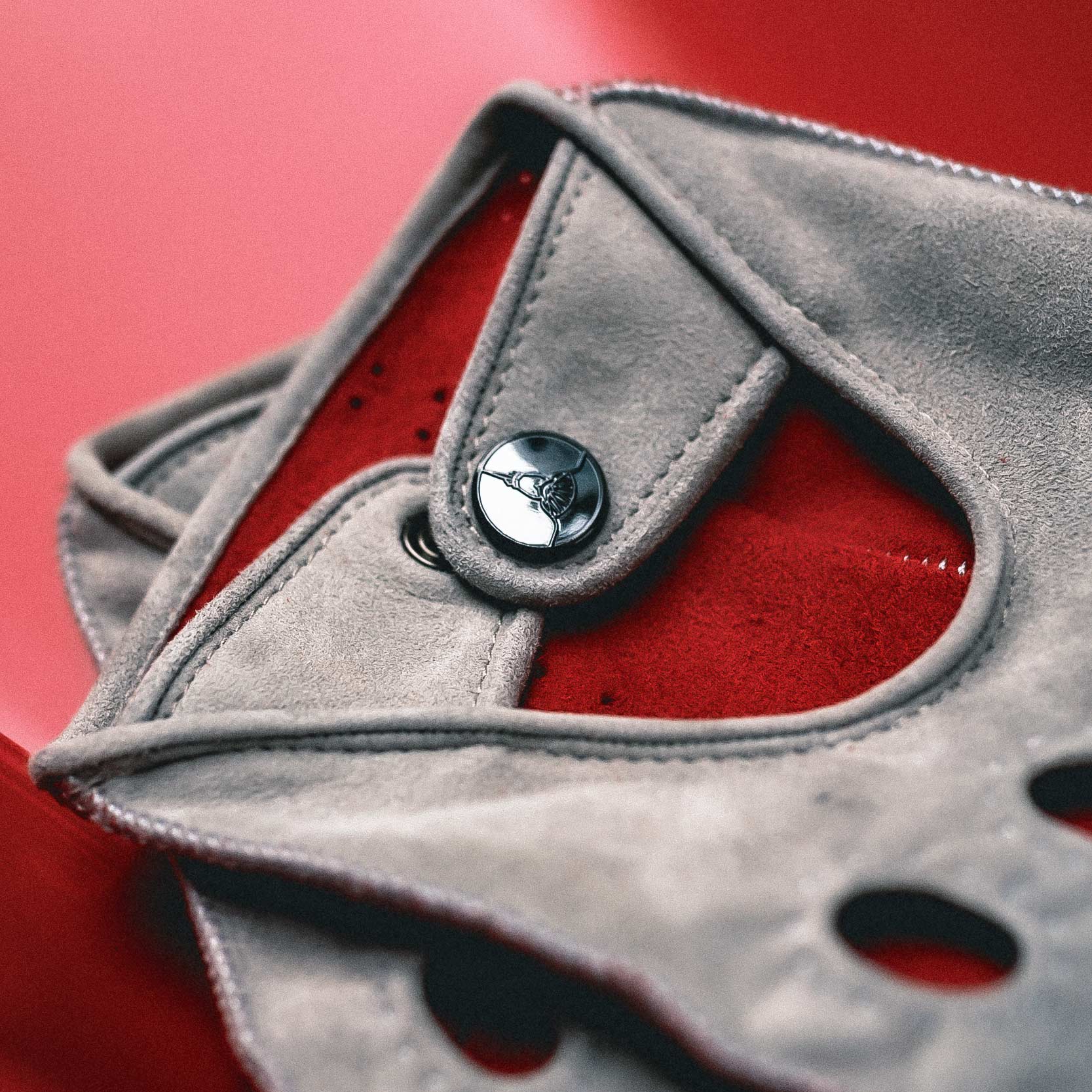 Gray suede clutch with a button detail on a red background