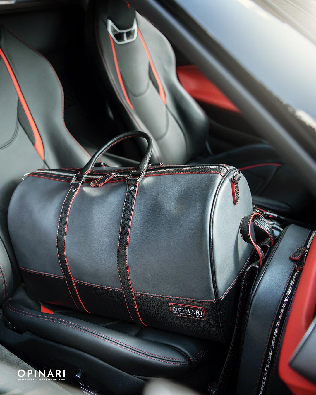 Gray duffel bag with red accents on a car seat, featuring the Opinari brand.
